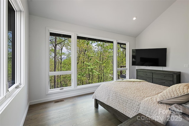 bedroom featuring baseboards, vaulted ceiling, wood finished floors, and visible vents