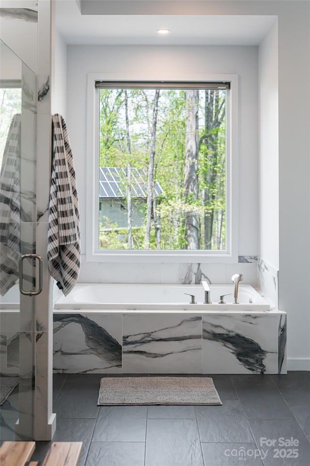 full bath with plenty of natural light, a stall shower, and a garden tub