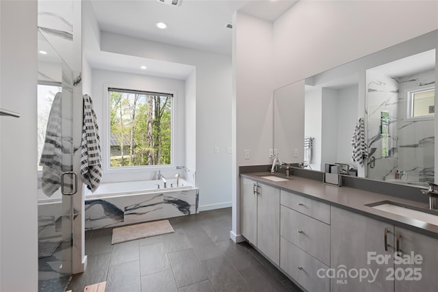 bathroom featuring double vanity, a wealth of natural light, a sink, and a stall shower