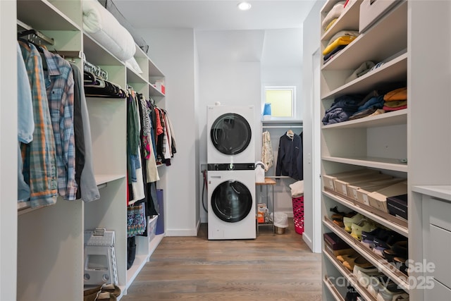 laundry area featuring recessed lighting, stacked washer / drying machine, wood finished floors, and laundry area