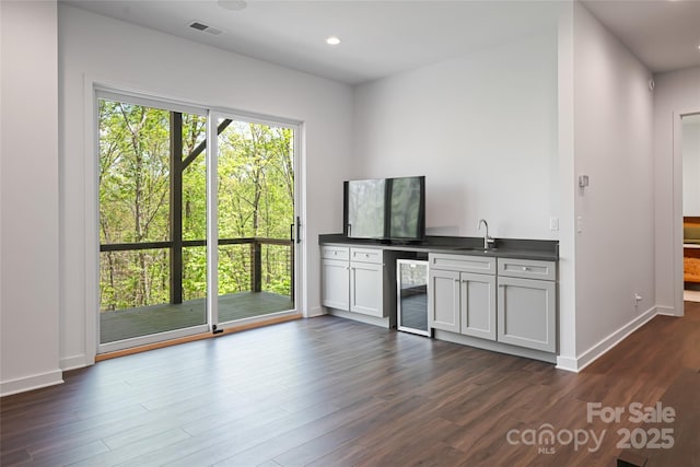 bar with visible vents, dark wood-style floors, beverage cooler, and indoor wet bar