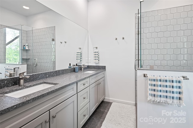 full bath featuring a sink, baseboards, a shower stall, and double vanity