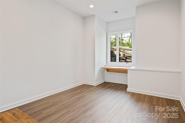 spare room with visible vents, recessed lighting, baseboards, and wood finished floors