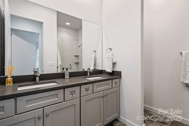 full bath with double vanity, baseboards, a sink, and a stall shower