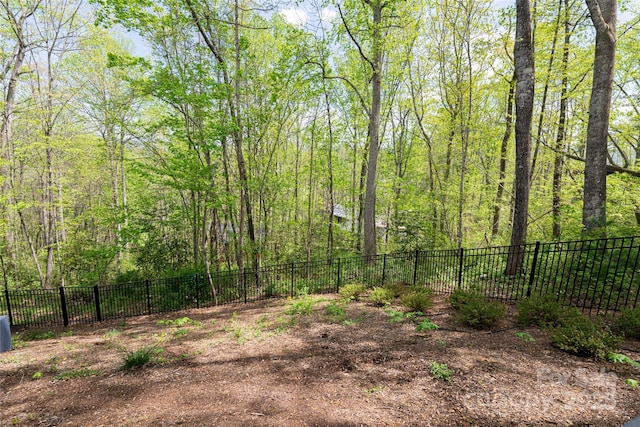 view of yard with fence and a wooded view