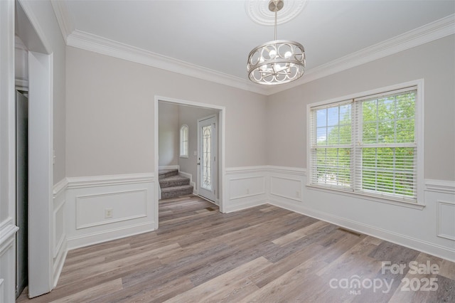 1033 Marguerite Dr, Lowell, NC 28098 - unfurnished dining area with an inviting chandelier, a wainscoted wall, crown molding, and light wood finished floors