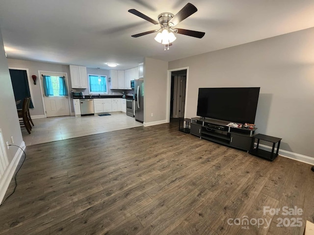 unfurnished living room featuring wood finished floors, baseboards, and ceiling fan
