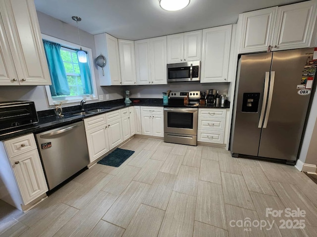 kitchen featuring appliances with stainless steel finishes, a toaster, wood finish floors, and a sink