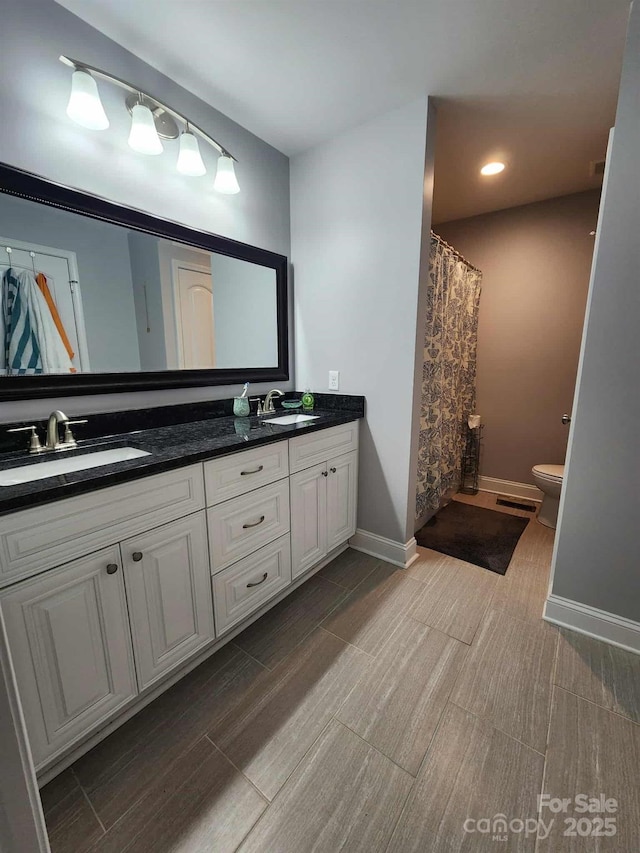 bathroom featuring double vanity, toilet, wood tiled floor, and a sink