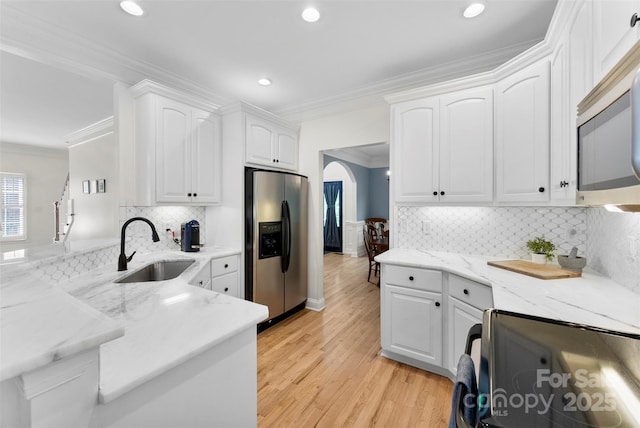 kitchen with white cabinetry, a sink, appliances with stainless steel finishes, recessed lighting, and ornamental molding