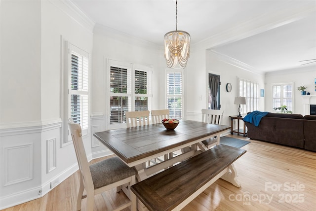 dining room with a chandelier, crown molding, and light wood finished floors