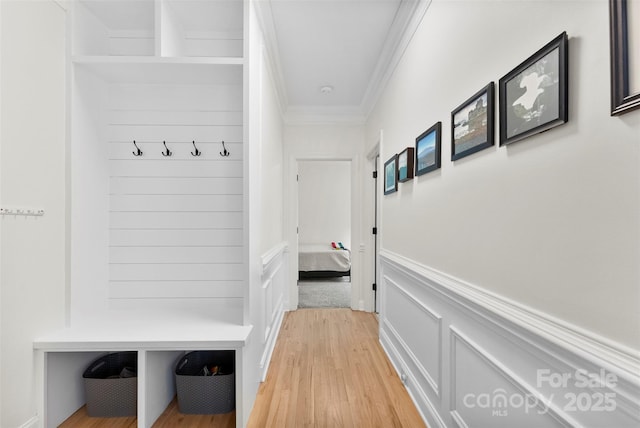 mudroom featuring crown molding, wainscoting, and light wood-style floors