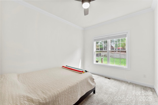carpeted bedroom with visible vents, a ceiling fan, ornamental molding, and baseboards