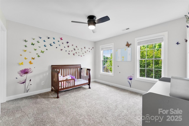 bedroom with carpet, visible vents, a crib, and baseboards