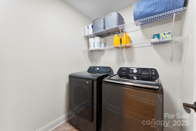 clothes washing area featuring tile patterned flooring, independent washer and dryer, laundry area, and baseboards