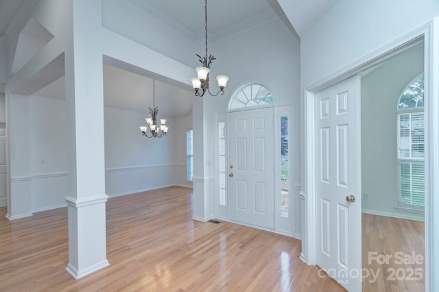 3226 Chatfield Ln SW, Concord, NC 28027 - entryway with light wood-type flooring, a healthy amount of sunlight, a notable chandelier, and decorative columns