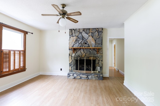 unfurnished living room featuring baseboards, a ceiling fan, wood finished floors, and a fireplace