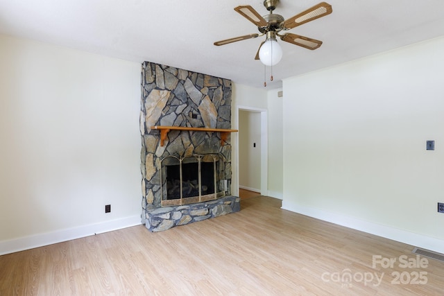 unfurnished living room featuring wood finished floors, visible vents, a ceiling fan, baseboards, and a fireplace