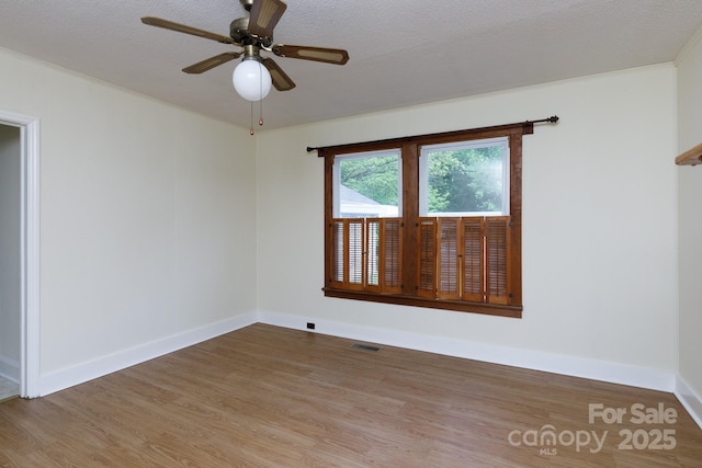 unfurnished room with visible vents, baseboards, a ceiling fan, and wood finished floors