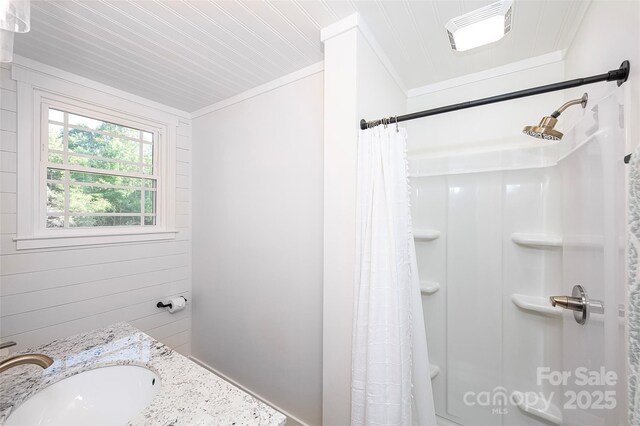 bathroom featuring a shower with shower curtain, visible vents, crown molding, and a sink