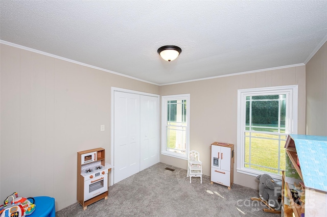 rec room with a textured ceiling, carpet floors, visible vents, and crown molding
