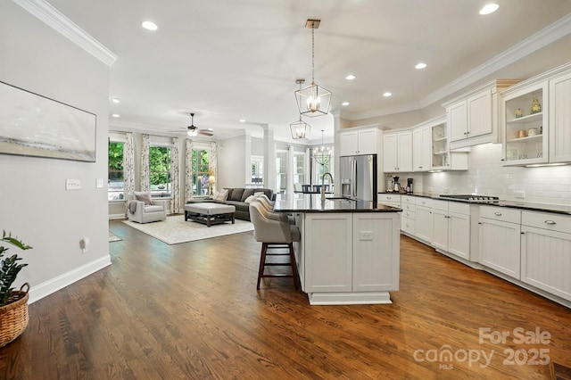 kitchen featuring stainless steel fridge, ornamental molding, a sink, and dark countertops