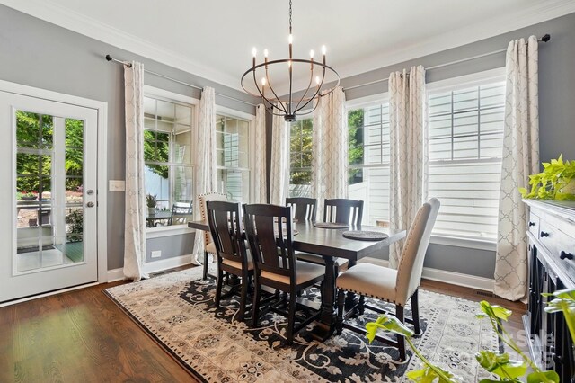 dining area featuring baseboards, a chandelier, ornamental molding, and wood finished floors
