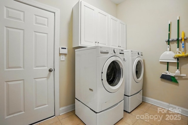 laundry area featuring separate washer and dryer, baseboards, cabinet space, and light tile patterned floors
