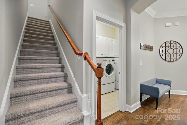 staircase featuring washer / dryer, baseboards, crown molding, and wood finished floors