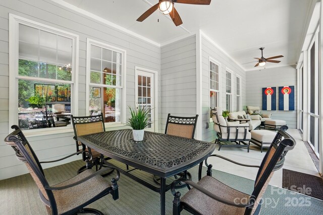 sunroom / solarium featuring ceiling fan and wood walls