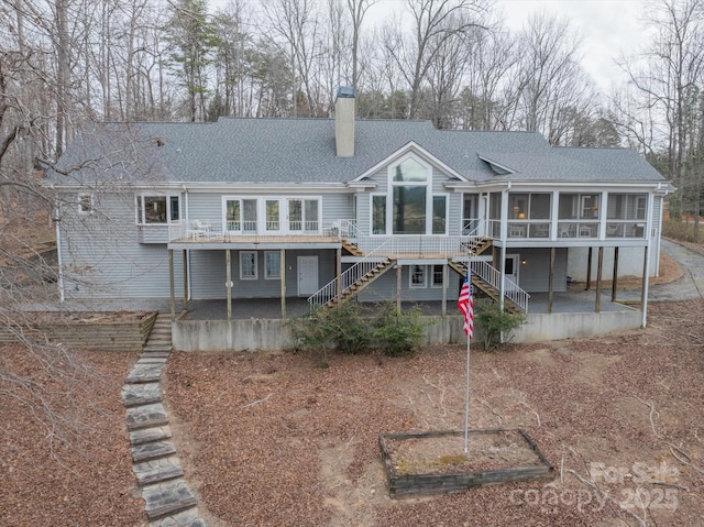 98 Fox Trl, Tryon, NC 28782 - back of house with a chimney, a patio area, a shingled roof, stairway, and a sunroom