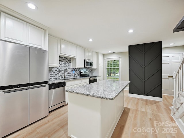 7004 Quail Hill Rd, Charlotte, NC 28210 - kitchen with white cabinetry, a sink, appliances with stainless steel finishes, and light wood-type flooring