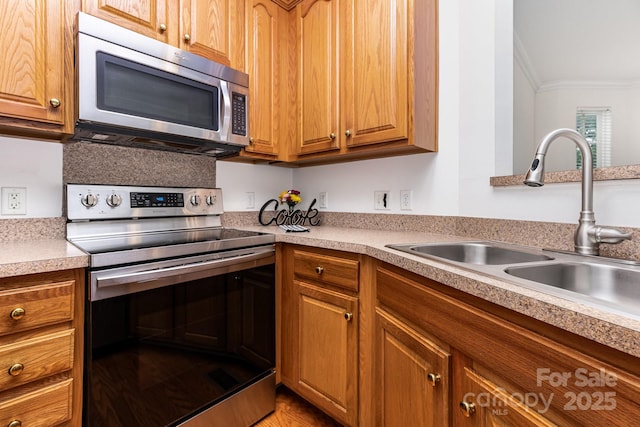 3158 Walnut Park Dr, Charlotte, NC 28262 - kitchen featuring appliances with stainless steel finishes, a sink, crown molding, light countertops, and brown cabinets