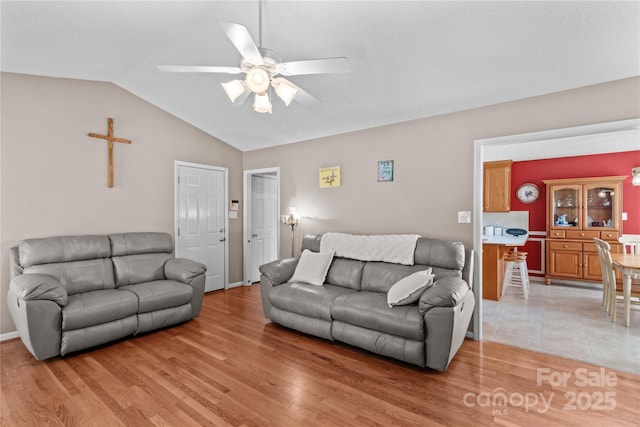 living area with vaulted ceiling, light wood-type flooring, and ceiling fan