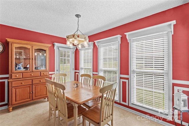 dining space featuring an inviting chandelier, a textured ceiling, and light tile patterned flooring