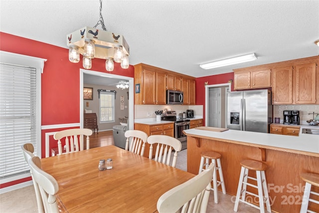 dining room with ceiling fan, baseboards, and a textured ceiling