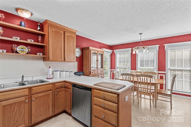 kitchen with a peninsula, dishwasher, a textured ceiling, and a sink