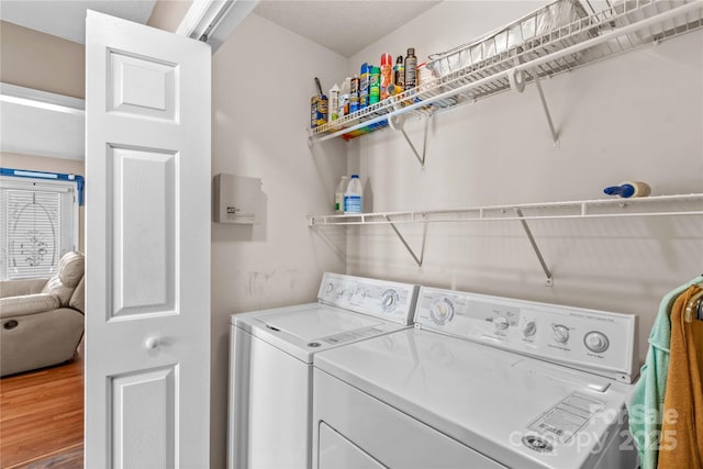 clothes washing area featuring wood finished floors, washer and dryer, and laundry area