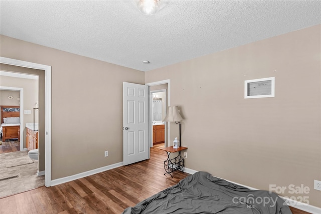 unfurnished bedroom featuring baseboards, wood finished floors, and a textured ceiling