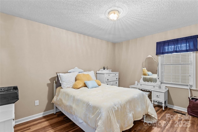 bedroom with visible vents, baseboards, wood finished floors, and a textured ceiling