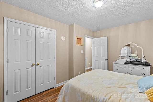 bedroom featuring baseboards, dark wood-style flooring, a textured ceiling, and a closet