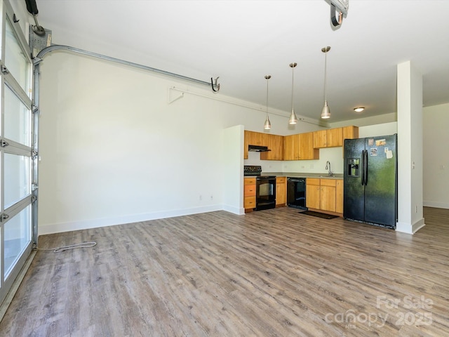1611 Central Ave Unit 406, Charlotte, NC 28205 - kitchen with wood finished floors, hanging light fixtures, under cabinet range hood, black appliances, and baseboards