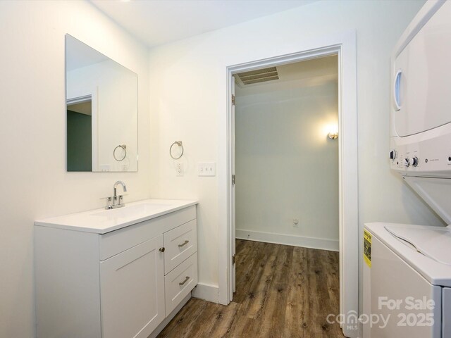 1611 Central Ave Unit 406, Charlotte, NC 28205 - half bath featuring stacked washer and clothes dryer, visible vents, baseboards, wood finished floors, and vanity