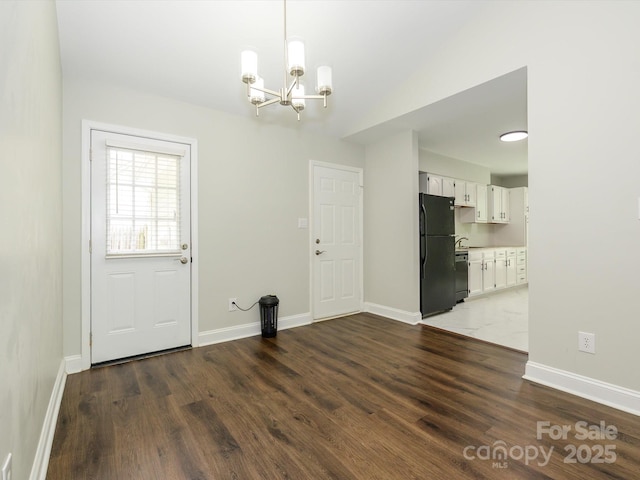 unfurnished dining area featuring baseboards, an inviting chandelier, and dark wood finished floors