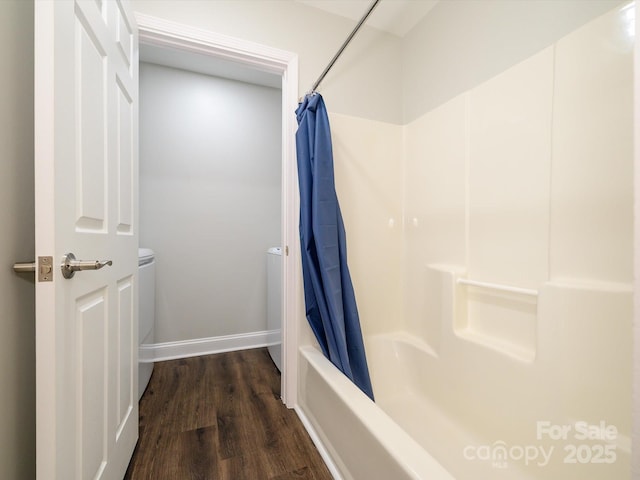 bathroom featuring baseboards, wood finished floors, and shower / tub combo with curtain