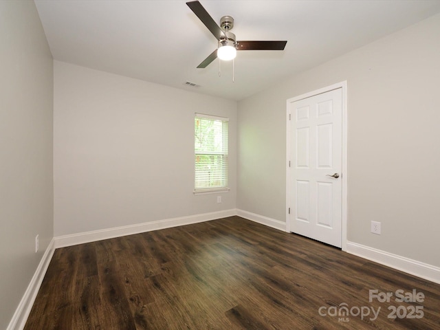unfurnished room featuring visible vents, a ceiling fan, baseboards, and dark wood-style flooring