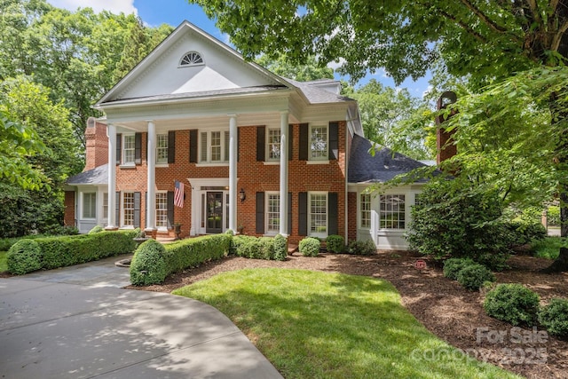 6824 N Baltusrol Ln, Charlotte, NC 28210 - neoclassical home with brick siding, a shingled roof, a front lawn, and a porch