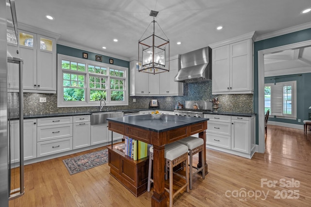 6824 N Baltusrol Ln, Charlotte, NC 28210 - kitchen with wall chimney exhaust hood, a sink, light wood-style floors, ornamental molding, and dark countertops