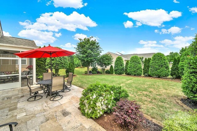 view of yard featuring a sunroom, outdoor dining area, and a patio