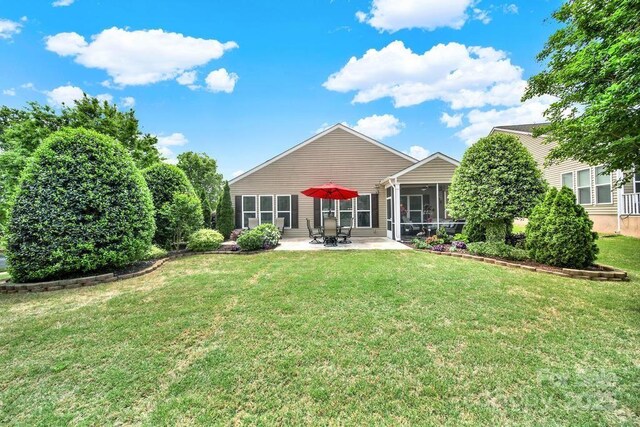 rear view of house with a patio area, a lawn, and a sunroom